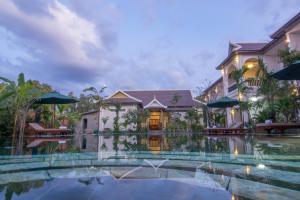 a house with a swimming pool in front of a building at De Arya Angkor Resort in Siem Reap