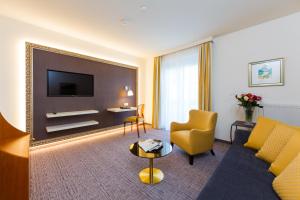 a living room with a couch and a tv at Hotel Goritschnigg in Velden am Wörthersee