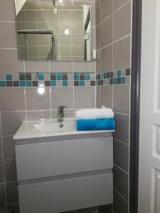 een badkamer met een witte wastafel en een spiegel bij Appartement à 500m de la plage in Mèze