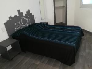 Bett mit schwarzer Decke in einem Zimmer in der Unterkunft Appartement à 500m de la plage in Mèze
