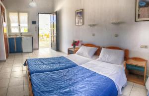 a bedroom with a large bed with blue and white sheets at Hotel Helena in Ios Chora