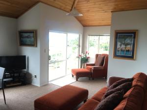 a living room with a couch and chairs and a television at Top of the Bay in Paihia