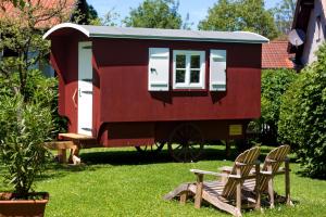 een rood tiny house in een yard met twee stoelen bij Haus am Salinenweg in Grassau