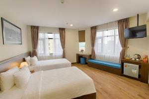 a hotel room with two beds and a flat screen tv at Central Hotel & Spa Danang in Da Nang