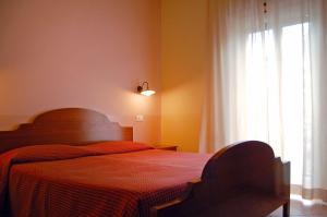 a bedroom with a bed with a red blanket and a window at Hotel Ristorante Benigni in Campagnano di Roma