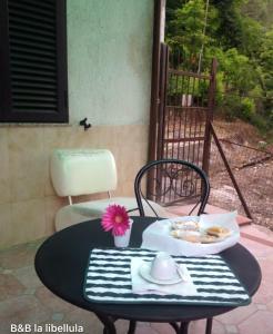 un tavolo con un piatto di cibo e un fiore sopra di B&B La Libellula a Pratella