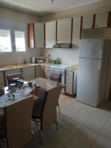 a kitchen with a table and a white refrigerator at Apartment Next to Coast in Nea Anchialos +10 photos