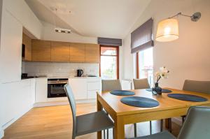 a kitchen and dining room with a wooden table and chairs at Grand Apartments - Neptun Park. in Gdańsk