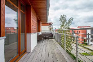 a balcony with a wooden deck with tables and chairs at Grand Apartments - Neptun Park. in Gdańsk