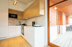 a kitchen with white cabinets and a sliding glass door at Grand Apartments - Neptun Park. in Gdańsk