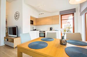 a kitchen and dining room with a wooden table and chairs at Grand Apartments - Neptun Park. in Gdańsk