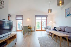 a living room with a couch and a tv at Grand Apartments - Neptun Park. in Gdańsk