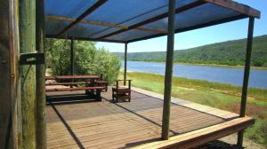 a wooden deck with benches and a view of a river at Koensrust Tented River Camp in Vermaaklikheid