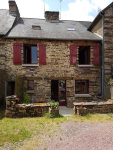 Casa de piedra antigua con ventanas de contraventanas rojas en Le Logis De Judicael en Paimpont