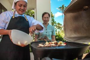 a woman is cooking food on a grill at Baan Sawan Villa in Bophut 