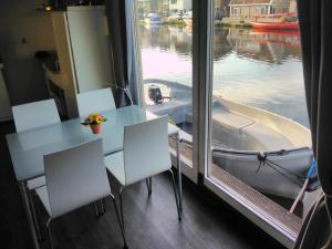 a table and chairs in front of a window with a boat at B&Boathouse Amsterdam with bikes and motorboat in Amsterdam