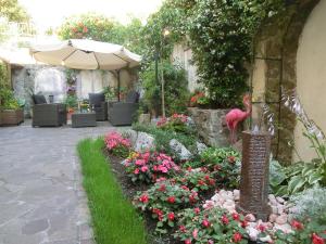 a garden with flowers and a bird statue and an umbrella at Le Rose in Trieste