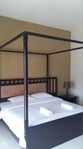 ein schwarzes Himmelbett mit weißer Bettwäsche und Kissen in der Unterkunft Lala House, Gold Coast Morib Resort in Banting