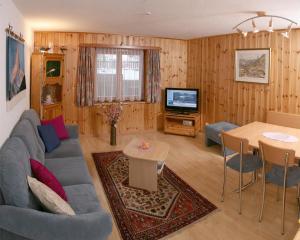 un salon avec un canapé bleu et une télévision dans l'établissement Chalet Medi, à Zermatt