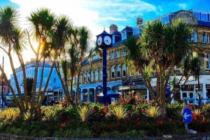 a clock tower in front of a building with palm trees at Cornerhouse Apartments Llandudno in Llandudno