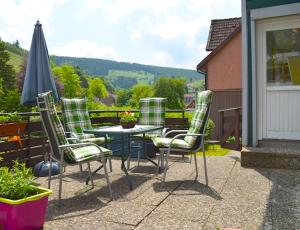 un patio con mesa, sillas y sombrilla en Ferienwohnung Pusteblume en Wildemann