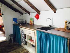 a kitchen with a sink and a counter with blue curtains at Veenhoes in Vriescheloo