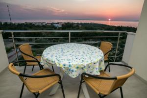 a table and chairs on a balcony with the sunset at Agata Apartments in Novalja