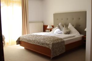 una camera da letto con un grande letto con lenzuola e cuscini bianchi di Seehotel Paulitsch a Velden am Wörthersee