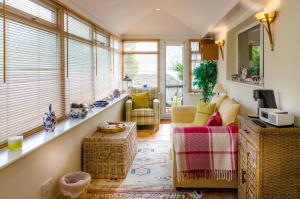 uma sala de estar com um sofá, cadeiras e janelas em Raikes Barn em Skipton