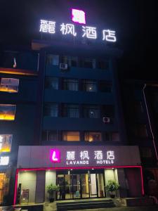 ein Gebäude mit Neonschildern in der Nacht in der Unterkunft Lavande Hotel Lanzhou in Lanzhou