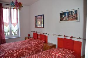 a bedroom with two red beds and a window at Gîte chez la Marie in Épinal