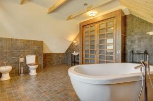 a large bathroom with a tub and a toilet at Country house Stirnamis in Mindūnai