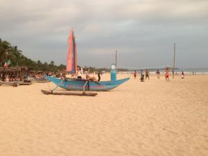 希卡杜瓦的住宿－Sundowners Guesthouse，海滩上的蓝色小船和海滩上的人们