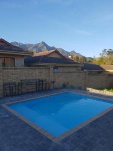 a large blue swimming pool next to a brick wall at Camello in George