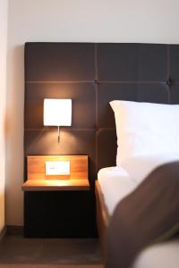 Una cama con mesita de noche con una lámpara. en Hotel Kunstmühle en Mindelheim