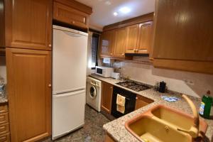 a kitchen with wooden cabinets and a white refrigerator at La Muralla Del Castillo in Chulilla +8 photos