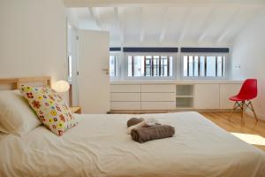 a bedroom with a large white bed with a red chair at Fisherman's House - a boat ride from Lisbon in Trafaria