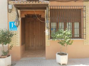 uma porta para um edifício com uma árvore em frente em Hospedería Ana Pilar em Porcuna