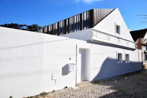 um edifício branco com uma varanda em cima em Fisherman's House - a boat ride from Lisbon em Trafaria