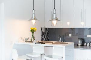 a kitchen with white cabinets and a vase of flowers at Apartament Casa de Kit in Pogorzelica