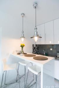 a kitchen with white cabinets and a white island with stools at Apartament Casa de Kit in Pogorzelica