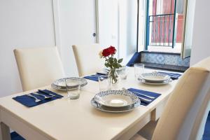 einen Tisch mit Platten und eine Vase mit einer roten Rose in der Unterkunft Neapolitan House in Neapel