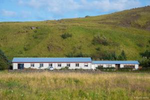 un edificio bianco con tetto blu accanto a una collina di Hótel Búrfell a Vík