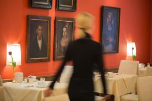 a woman walking through a dining room with tables at Hotel Elefant in Salzburg