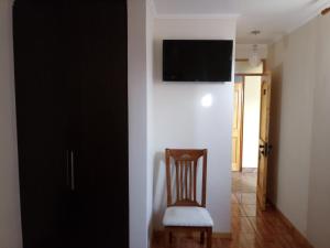 a room with a chair and a television on a wall at Casa Huespedes Angoba in Arica