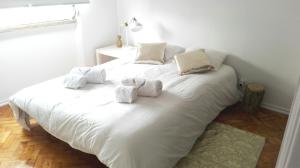 a white bed with three stuffed animals on it at Golden Apartment City Center in Lisbon