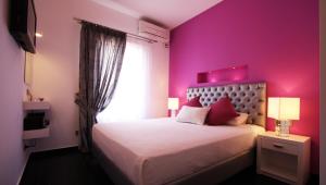 a pink bedroom with a bed and a window at Efharis in Kamares