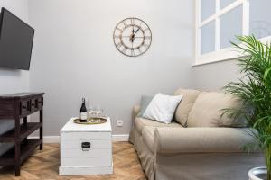 a living room with a couch and a clock on the wall at Apartment Nearto Old Town Kraszewskiego street in Krakow