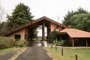 a red brick building with a gate and a driveway at Virá Charme Resort in Fernandes Pinheiro