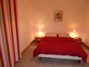 a bedroom with a red bed with two lamps on two tables at Villa Blanche in Loix